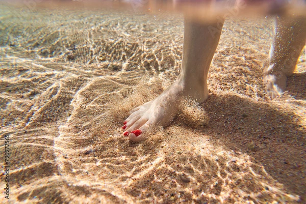 Obraz A man walks along the sea beach along the coastline and touches the sandy bottom with his feet