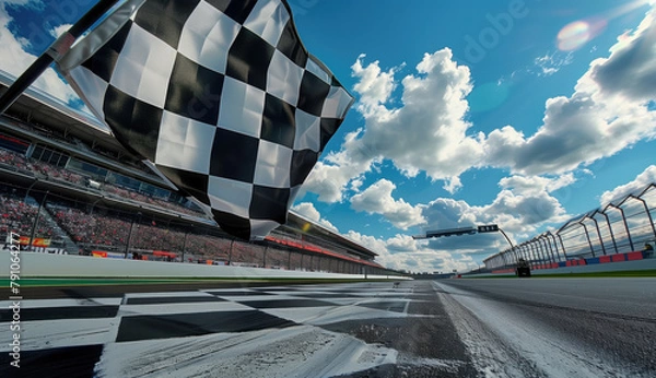 Fototapeta A checkered flag is flying in the air above a race track