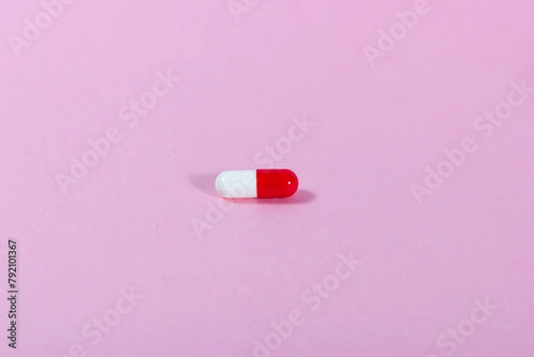 Obraz Close-up of a red and white medicinal tablet on a pink background.