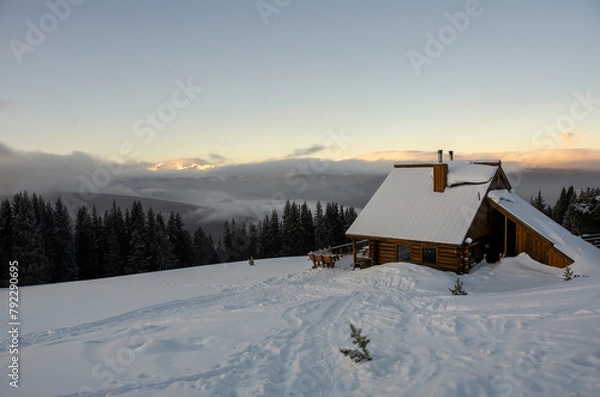 Fototapeta a cabin in the snowy woods at sunrise