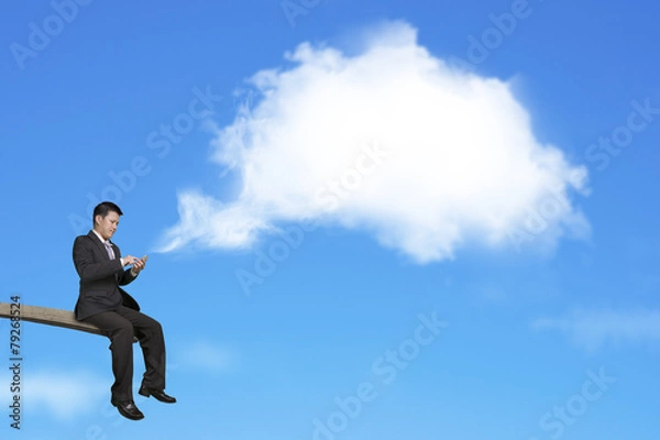 Fototapeta Using mobile businessman on springboard with white thought bubbl