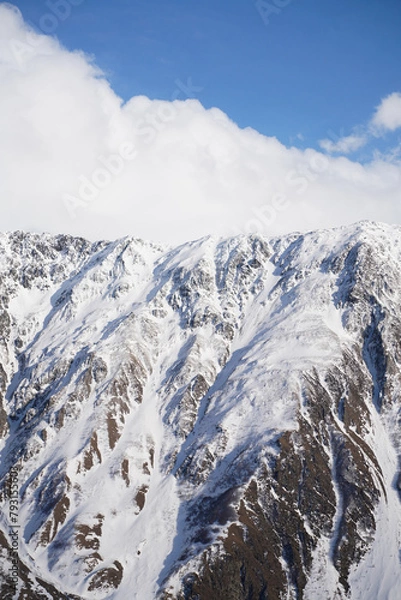 Fototapeta Snow-capped mountain range peaks under blue sky and white clouds, sunny day, Gergeti Trinity Church, Stepantsminda, Georgia