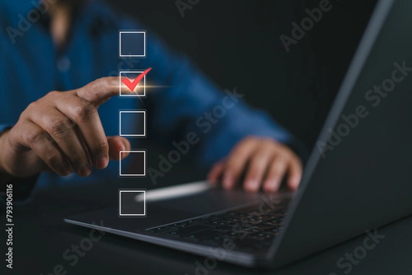 Obraz Checklist concept. Businessman using laptop tick correct mark in checkbox on virtual screen.