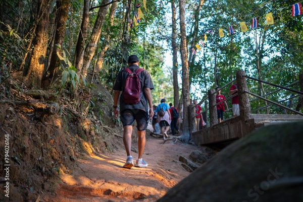 Fototapeta Asian tourists are walking up Khao Khitchakut, through large trees in the forest, tourist attraction Chanthaburi, Thailand.