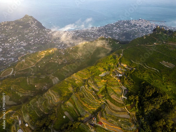 Fototapeta Aerial view at dawn from Mount Epomeo in Ischia. Flight in the clouds with a sea view