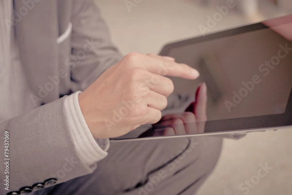 Fototapeta Businessman using electronic tablet pc. He is sitting on a stair