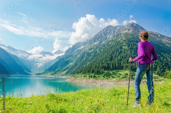 Obraz A young mountaineer stands beside an azure mountain lake