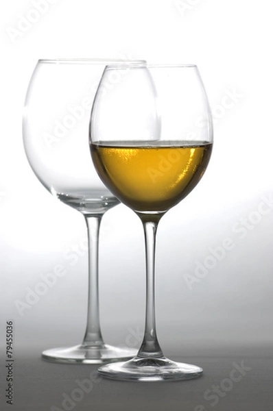 Obraz Two tall glasses, empty and filled with white wine
