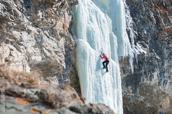 Fototapeta climber ascends the vertical icefall
