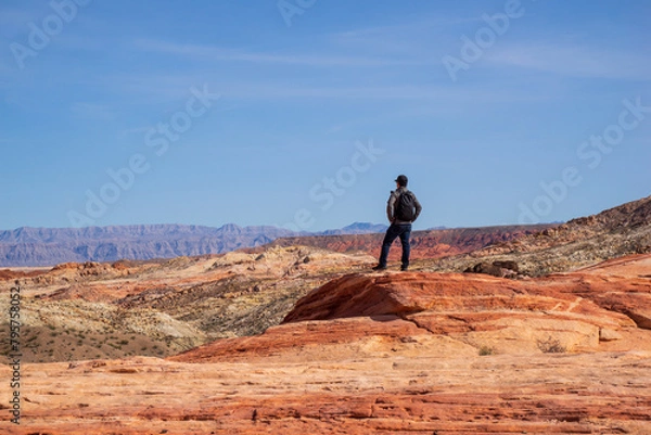 Fototapeta A man is standing and enjoying the spectacular view of Valley of Fire. It is one of geologic wonderland with 2000 year old petroglyphs carved into massive red sandstone formations in the Mohave Desert