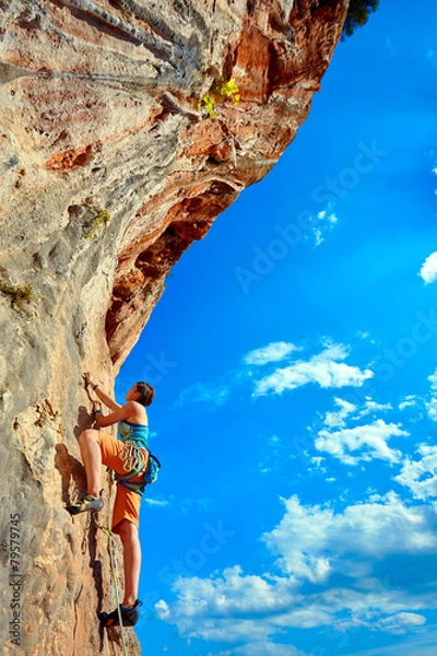 Obraz Rock climber climbing up a cliff