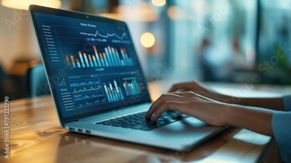 Obraz Close up view of a person's hand operating a laptop at a work desk as financial analysis data