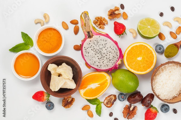 Fototapeta Assorted fresh fruits and nuts on a white background. Ingredients for a healthy dish