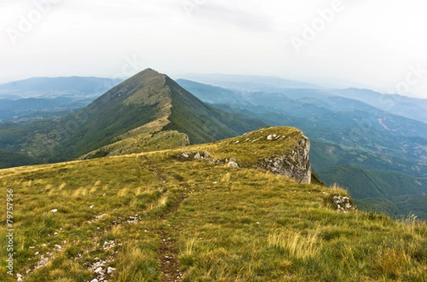 Fototapeta Rocks and cliffs under dark clouds trekking path at Suva Planina