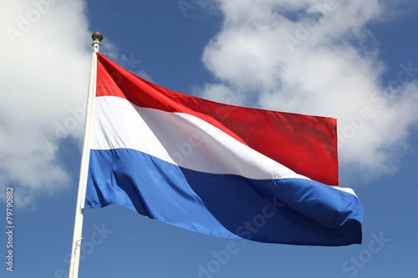 Fototapeta Dutch national flag on liberty day against blue sky with clouds