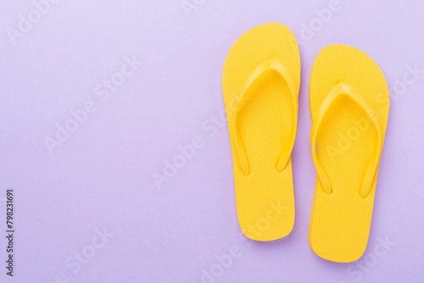 Fototapeta Bright yellow flip-flops on color background, top view. Summer concept