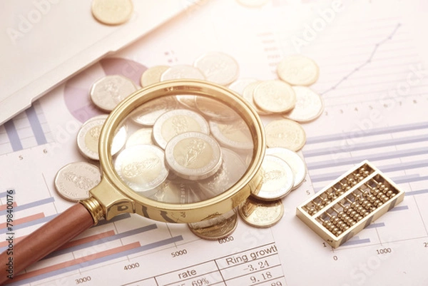 Fototapeta Coins, magnifying glasses, and abacus placed on data sheets - Monetary Finance