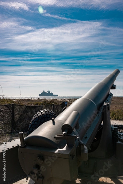 Fototapeta cannon on the beach With a large military ship in the background 