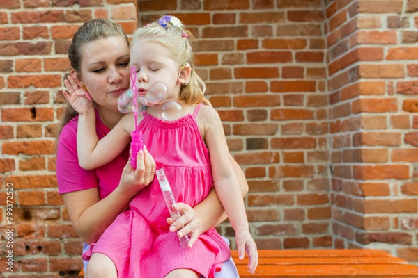 Fototapeta Deaf child with cochlear implant for hearing audio and aid for impairment having fun and laughs with mother outdoor in summer. Sound fitting device to help with communication listening and interaction