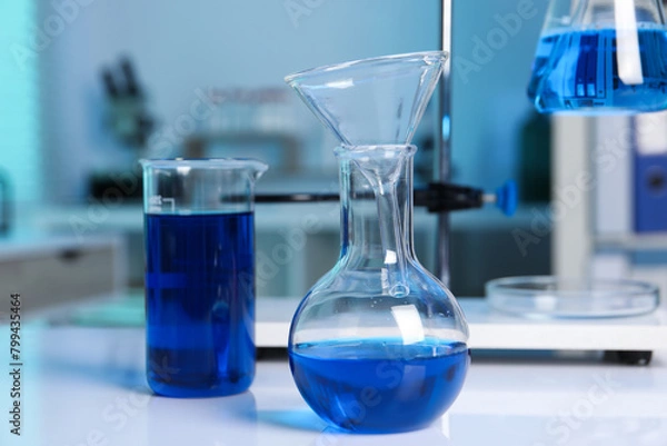 Fototapeta Laboratory analysis. Flasks and beaker with blue liquid on white table indoors