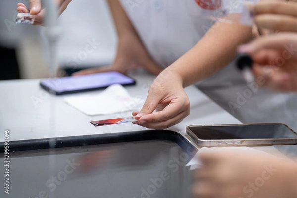 Fototapeta A person is holding a phone and a tablet, and another person is holding a bottle