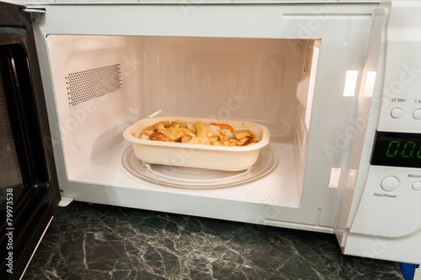 Obraz View of open microwave oven with delivery service food inside