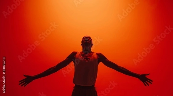 Fototapeta Man with open arms embracing light in a vibrant red ambiance.