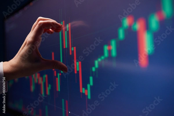 Obraz Finger to the graph on the monitor. Team of stockbrokers are having a conversation in a office with multiple display screens.