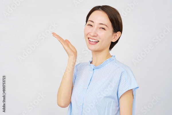 Fototapeta 手の平で左を指すミドルエイジの女性　白背景