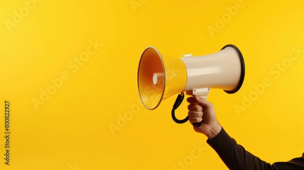 Fototapeta Holding megaphone in hand on yellow background.