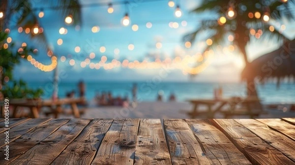 Fototapeta An empty wooden table with a blurred beach party in the background, setting the stage for summer gatherings.
