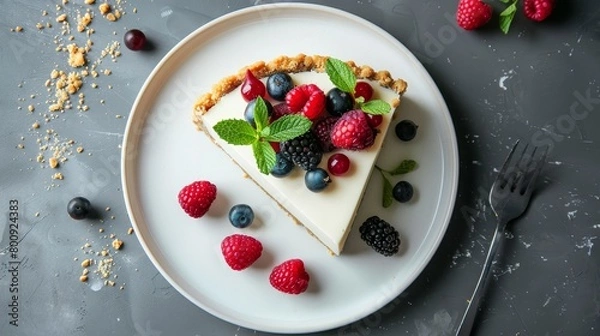 Fototapeta Top view of a creamy cheesecake with a golden crust, garnished with fresh berries and mint, on a minimalist white plate, isolated background, studio lighting
