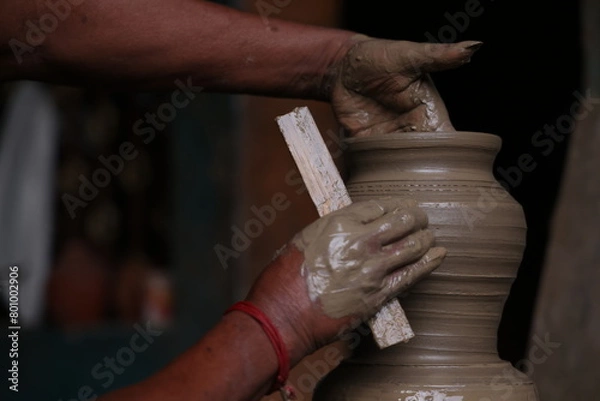 Fototapeta The potter works on a pottery wheel to made of soft colored clay, retro style toned Clay pots with hand and equipment