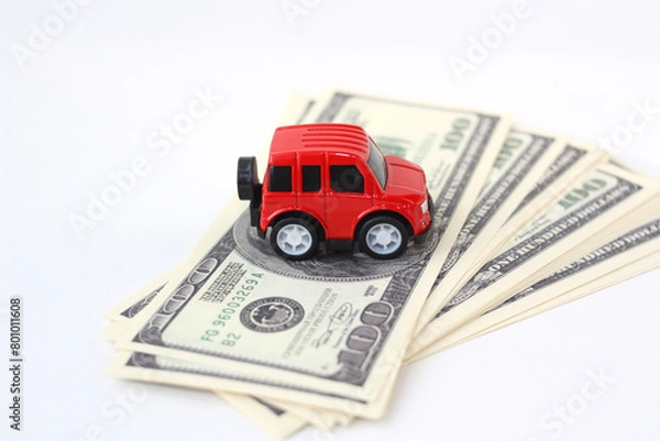 Obraz A red toy car sits on a stack of dollars.
Concept - buying a car, selling, paying off a loan, leasing, repairing. Cost concept for paying car bills.