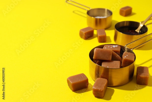 Obraz Cubes of salted caramel with salt on a yellow background