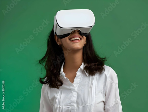 Fototapeta Portrait of happy young indian woman wearing white augmented virtual reality glasses on green color studio background with copy space