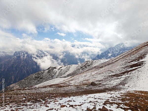 Obraz Snow-dusted mountain ridge with rugged terrain under a cloudy sky