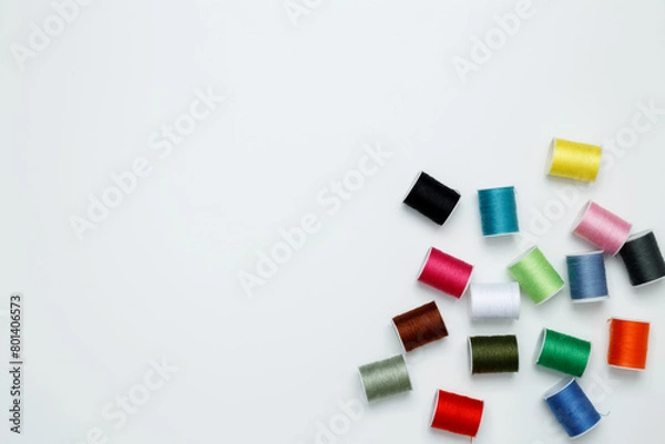 Fototapeta Multicolored sewing threads on white background. Top view, copy space