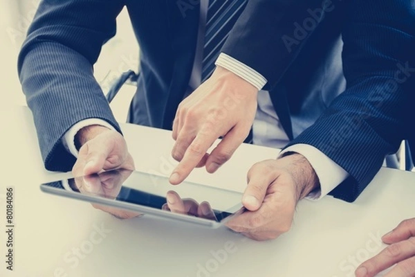 Fototapeta Businessmen using tablet computer with one hand touching screen