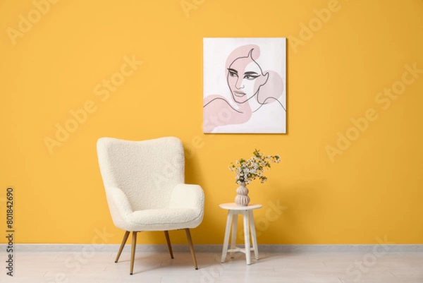 Fototapeta Armchair and vase with blooming branches on table near orange wall