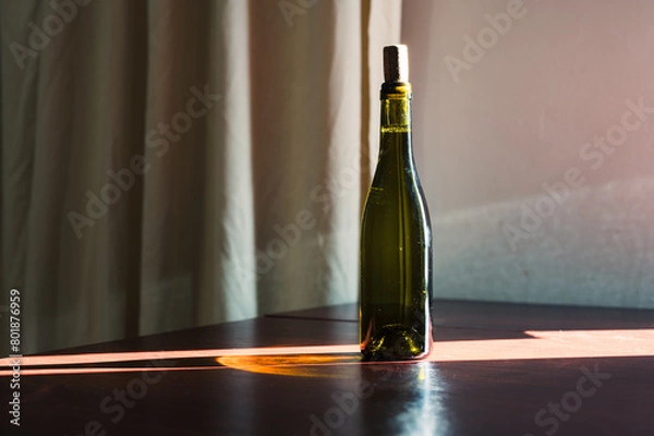 Fototapeta Bottle of wine with cork standing on the table. Green glass and sun ray. Style decor image