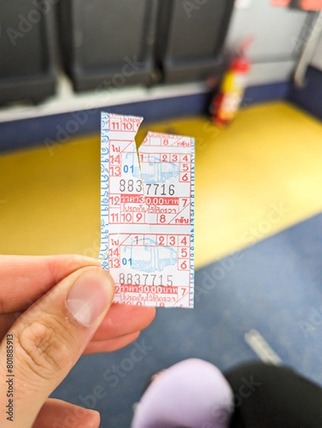 Fototapeta A hand holding a bus ticket in bus.