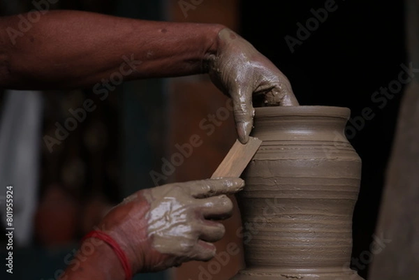 Obraz The potter works on a pottery wheel to made of soft colored clay, retro style toned Clay pots with hand and equipment