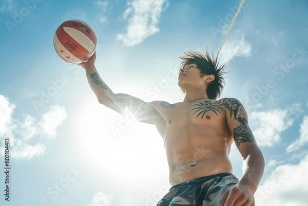 Fototapeta A man is playing with a volleyball in the sun