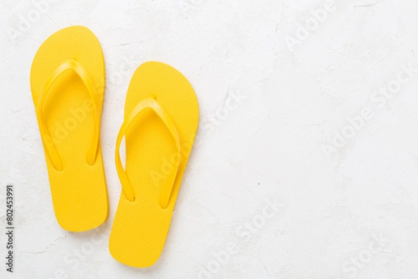 Fototapeta Bright yellow flip-flops on concrete background, top view. Summer concept