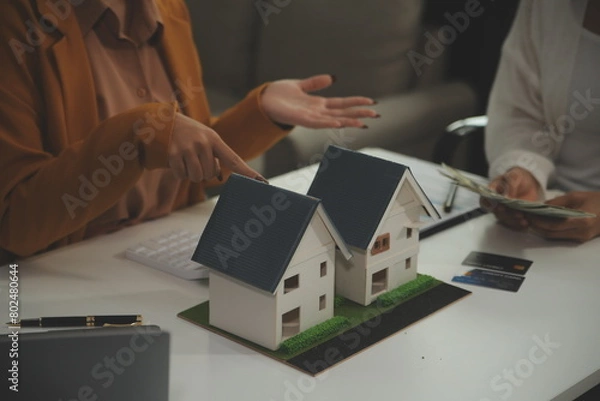 Fototapeta Discussion with a real estate agent, House model with agent and customer discussing for the contract to buy, get insurance or loan real estate or property.