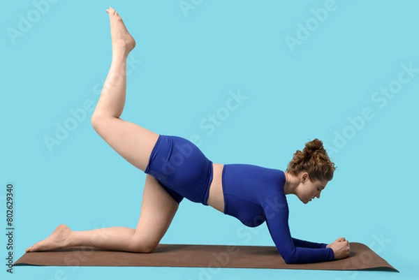 Fototapeta Sporty young woman doing yoga on  blue background