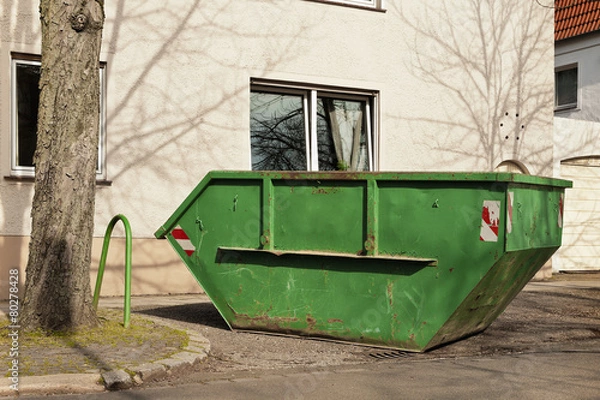 Obraz Ein grüner Container für Abfall steht vor einem Wohnhaus