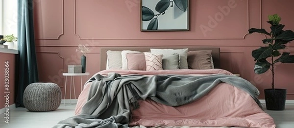 Fototapeta In a modern bedroom interior, there is a grey blanket placed on a pink bed against the wall with a poster.