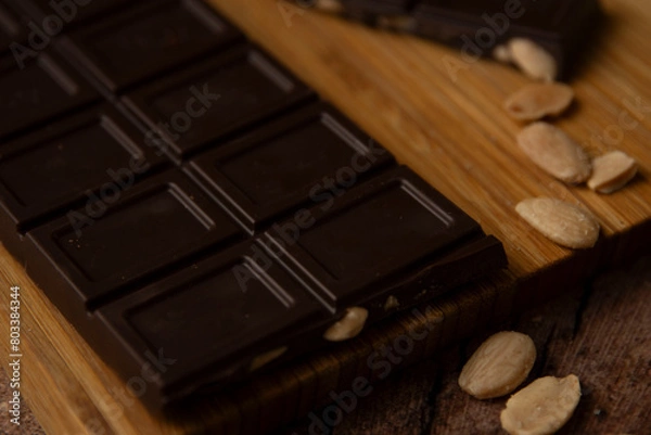 Obraz Tableta de chocolate negro con almendras sobre tabla de madera